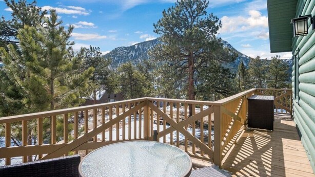A wooden deck with a glass table and chairs, overlooking a mountainous landscape. - RMNP,Longs Peak Views,Fireplace,Grill,Deck,Mtn Neighborhood Above Estes Park (Estes Park)