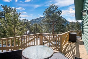 A wooden deck with a glass table and chairs, overlooking a mountainous landscape. - RMNP,Longs Peak Views,Fireplace,Grill,Deck,Mtn Neighborhood Above Estes Park (Estes Park)