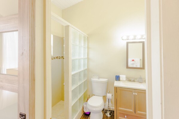 Ein Badezimmer mit Toilette, Waschbecken, Spiegel und Duschbereich.