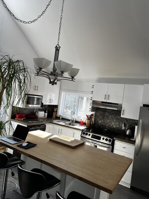 A modern kitchen with white cabinets, a wooden island, and a stainless steel refrigerator.
