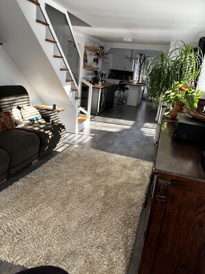 A modern loft-style living space with a staircase, kitchen, and dining area.