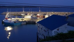 A marina with several boats docked, a stone breakwater, and a building with a blue roof. - Waterfront Acadian Home on Mavillette Beach at Cape St. Marys (Church Point)