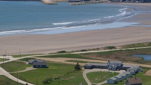 A coastal town with a beach, houses, and a lighthouse. - Waterfront Acadian Home on Mavillette Beach at Cape St. Marys (Church Point)