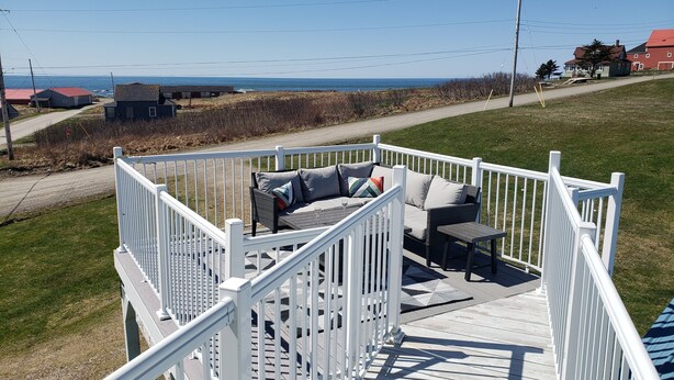 A deck with outdoor furniture, a railing, and a view of the ocean. - Waterfront Acadian Home on Mavillette Beach at Cape St. Marys (Church Point)