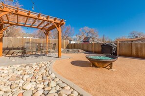 A backyard with a pergola, outdoor seating, a fire pit, and a wooden fence. - Bunk A: Dog Run and Firepit Fun (Fruita)