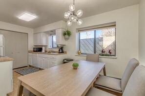 A modern kitchen with white cabinets, a wooden dining table, and a chandelier. - Bunk A: Dog Run and Firepit Fun (Fruita)