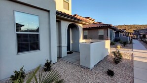 A modern residential building with a patio area, a small garden, and a clear sky. - Escondido Luxury Resort, pool, slide, pickleball, 4 bedrooms, bunks, 2car garage (Washington)