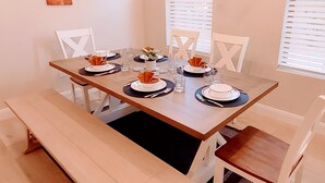 A dining table set for four with white chairs, a bench, and a window with blinds. - Escondido Luxury Resort, pool, slide, pickleball, 4 bedrooms, bunks, 2car garage (Washington)