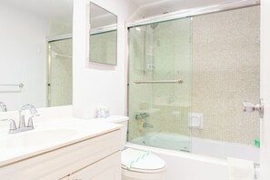 A modern bathroom with a glass shower enclosure, a white sink with chrome fixtures, and a large mirror. - Komffy Apt w/2 Queen Beds and canal view at Tides (Hollywood)