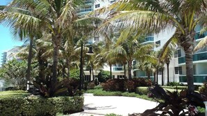 Ein modernes Hotel mit mehreren Etagen, Palmen und einem gepflegten Gartenbereich.