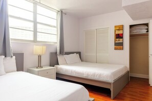 A hotel room with two beds, a bedside table with a lamp, a closet with sliding doors, and a window with curtains. - Komffy Apt w/2 Queen Beds and canal view at Tides (Hollywood)