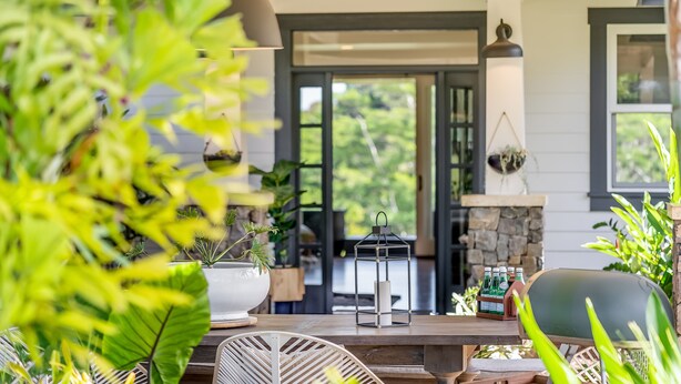 Une terrasse en bois avec des meubles d’extérieur, une lanterne suspendue et une cheminée en pierre.