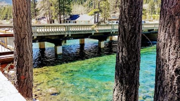 Un pont enjambant une rivière aux eaux claires, avec une maison en arrière-plan.