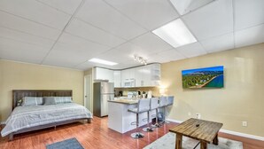 Une chambre d’hôtel de taille réduite, comprenant un lit, une kitchenette et un petit coin repas.