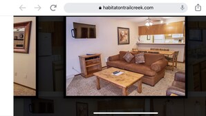 Ein Wohnzimmer mit braunem Sofa, Couchtisch aus Holz und einem Fernseher.