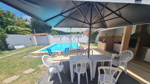 A backyard with a swimming pool, patio furniture, and a barbecue area.