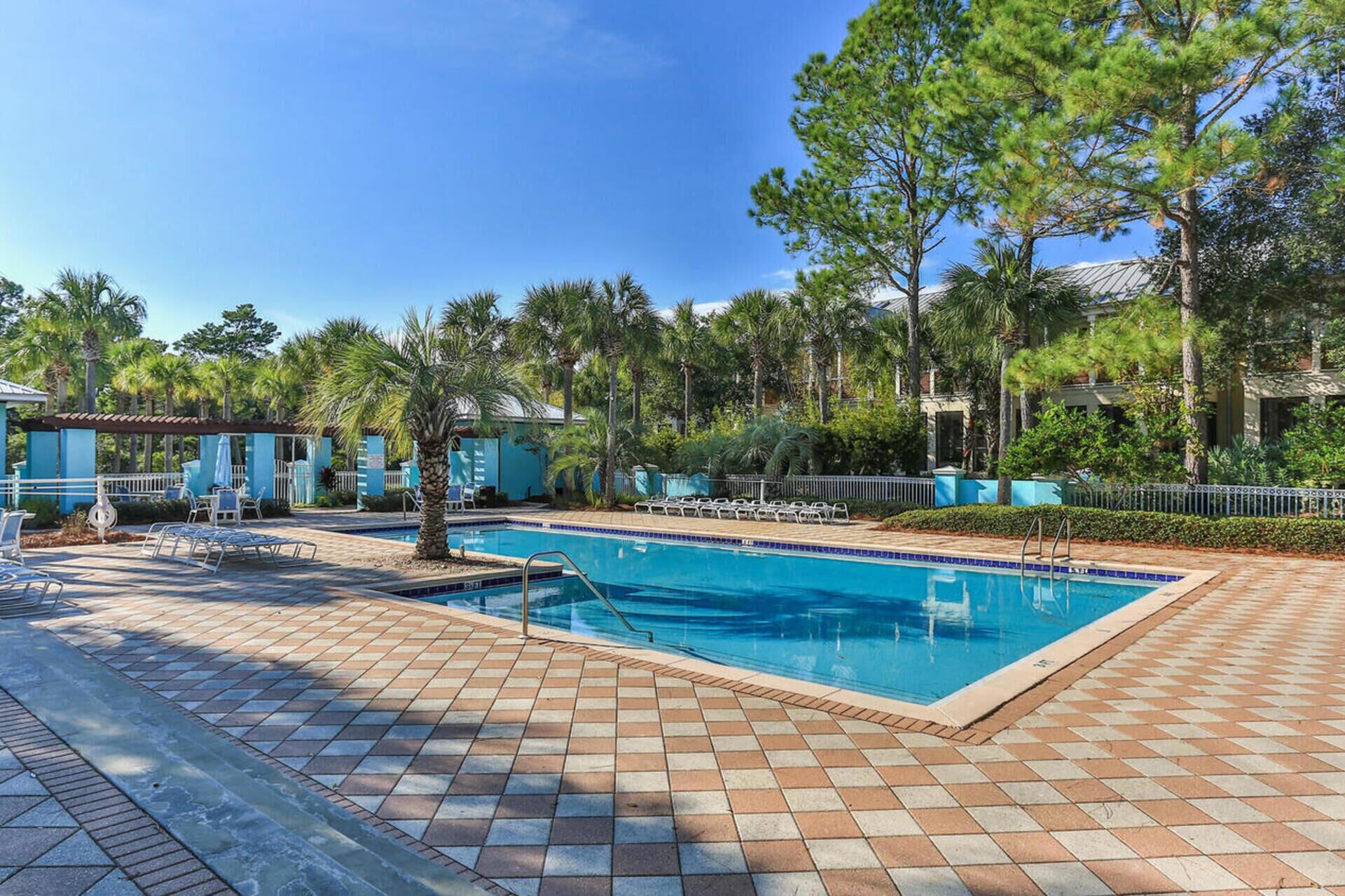 Una piscina con sillas de descanso y palmeras.