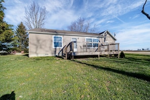 A single-story house with a front deck, a small porch, and a visible garage door. - Deer Brook Cottage (Wilmington)