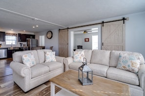 A living room with two sofas, a coffee table, and a dining area with a kitchen in the background. - Deer Brook Cottage (Wilmington)