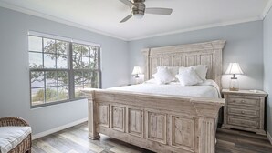 Ein Schlafzimmer mit einem großen Bett, zwei Nachttischen, einem Deckenventilator und einem Fenster mit Blick.