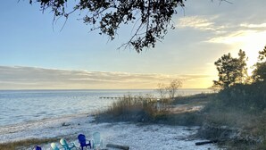 Ein Strand mit Stühlen und einer Feuerstelle, mit Blick aufs Meer.