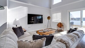 A modern living room with a large flat-screen TV, a wooden coffee table, and a sofa. - Deer Brook Lake House (Jamestown)