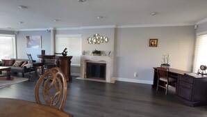 A spacious living room with a fireplace, a dining area with a wooden table and chairs, and a separate workspace with a desk and chair. - Lakefront 3 Bedroom house with breath taking views (Agoura Hills)