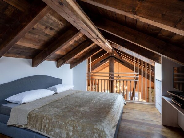 A bedroom with a sloped ceiling, a bed, a TV, and a view of the outside. - Sant'Evasio by Interhome (Ovada)