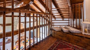 A rustic attic room with exposed wooden beams, a dining table set with plates, and a red patterned rug. - Sant'Evasio by Interhome (Ovada)