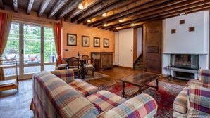 A cozy living room with wooden beams, plaid sofas, a fireplace, and a dining area with chairs and a table. - Sant'Evasio by Interhome (Ovada)