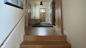A wooden staircase leading to a door at the end of a hallway with a framed painting on the wall.
