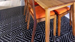 A dining area with a wooden table and chairs, a patterned rug, and two framed posters on the wall. - Stylish Bondi Beach pad moments from sand & surf (Bondi Beach)