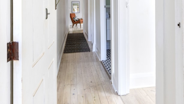 A hallway with white doors, a wooden floor, and a black doormat. - Stylish Bondi Beach pad moments from sand & surf (Bondi Beach)