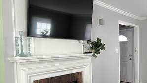 A living room with a fireplace, a mounted TV, and a door leading to another room. - Capeside Cottage (La Crosse)