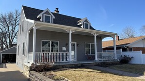 A two-story house with a porch, a garage, and a well-maintained lawn. - Capeside Cottage (La Crosse)