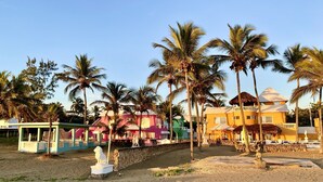 Un resort frente al mar con edificios coloridos, palmeras y una playa de arena.