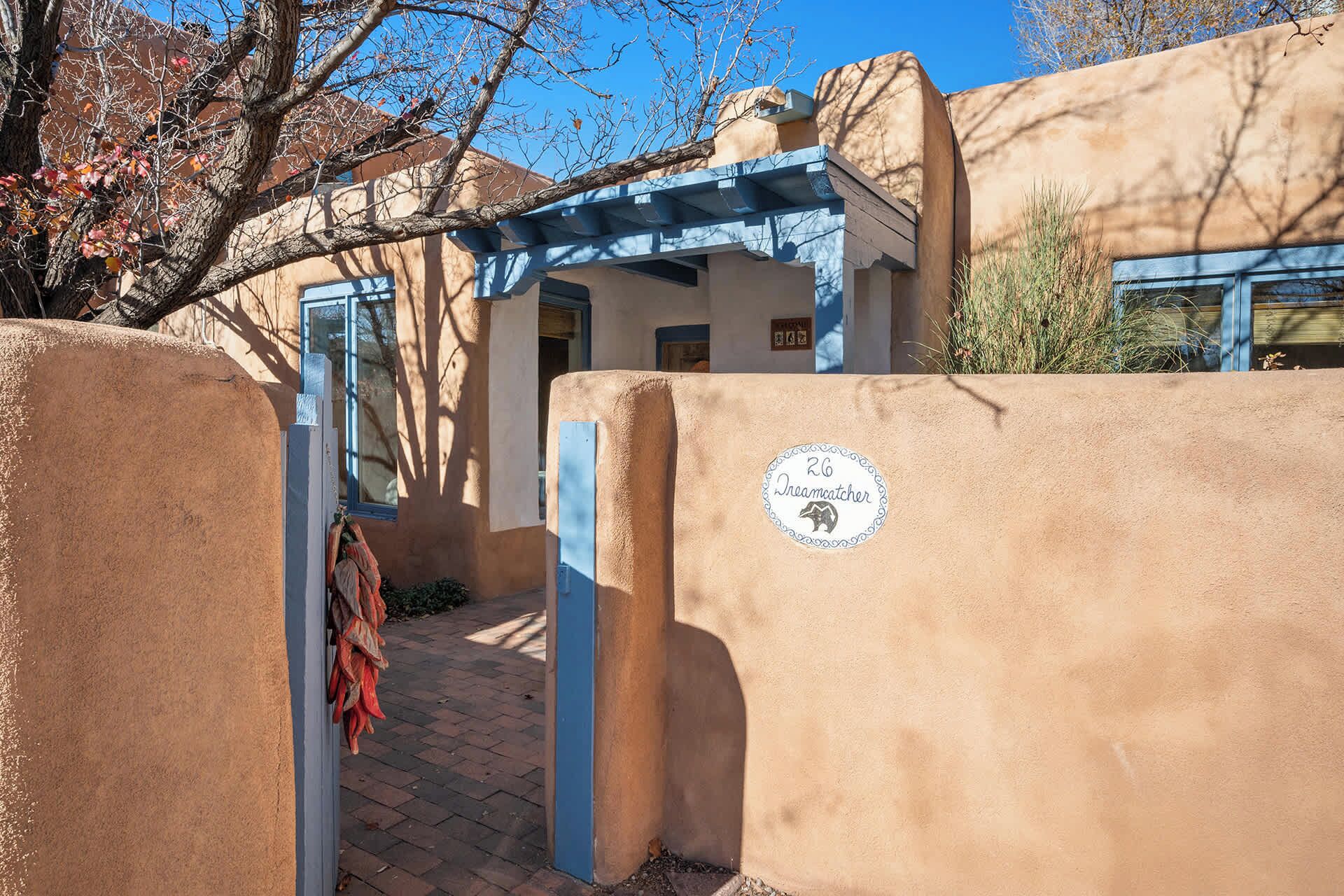 Un bâtiment traditionnel en adobe, avec une porte bleue et une enseigne indiquant « 26 Dreamcatcher ».