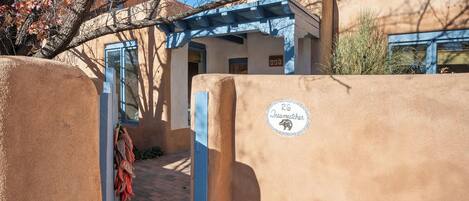 Un bâtiment traditionnel en adobe, avec une porte bleue et une enseigne indiquant « 26 Dreamcatcher ».