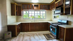 A kitchen with dark wooden cabinets, a marble floor, a window with a view, and a stove. - The Best 2 Bedrooms Townhouse in Montego Bay! (Montego Bay)