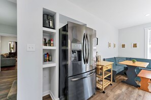 A modern kitchen with a stainless steel refrigerator, wooden table, and built-in shelves.