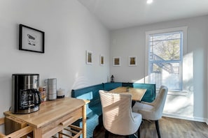 A compact living space with a kitchenette, a dining area, and a window with blinds.