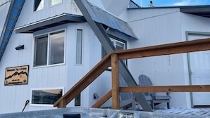 A modern house with a unique sloped roof and a hot tub area.