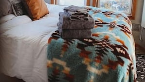 A bedroom with a bed, a blanket, and a mounted animal head on the wall.