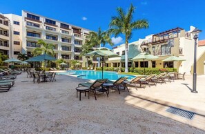 Un hôtel doté d’une piscine, de chaises longues et de palmiers.