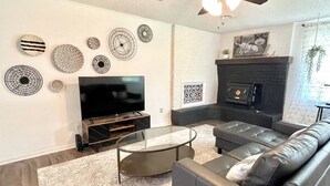Ein modernes Wohnzimmer mit Flachbildfernseher, Ledersofa und dekorativer Wandkunst.