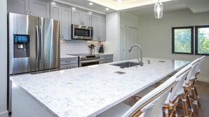 A modern kitchen with a large island, stainless steel appliances, and a built-in microwave.