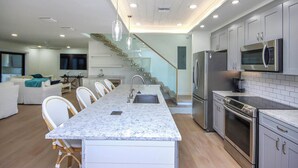 A modern kitchen with a central island, stainless steel appliances, and a staircase leading to an upper level.