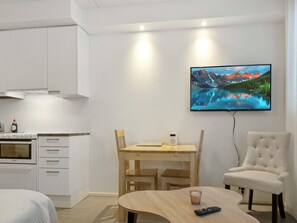 A modern kitchen with white cabinets, a built-in oven, and a dining area with a wooden table and chairs.