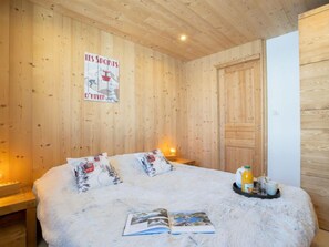 A cozy room with wooden walls, a bed with white bedding, a poster on the wall, and a breakfast tray on the bed.