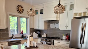 Cozinha moderna com ilha grande, cadeiras de madeira e luminárias pendentes.